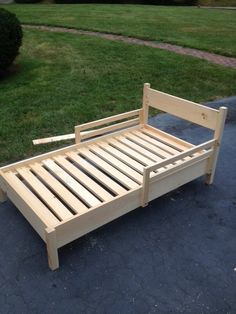 a wooden bed frame sitting on top of a sidewalk