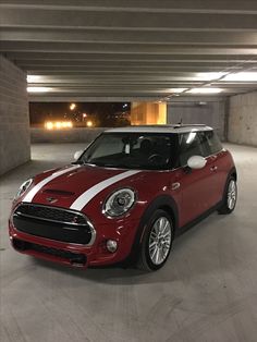 a red and white mini cooper parked in a parking garage with no one around it