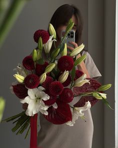 a woman taking a selfie while holding a bouquet of flowers