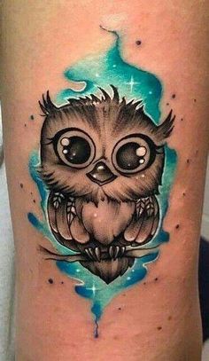 an owl tattoo on the thigh with blue watercolors and stars in the background