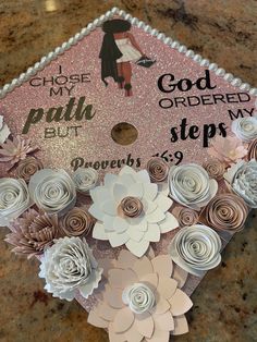 a graduation cap decorated with paper flowers on top of a granite countertop that reads, choose my path, god ordered me