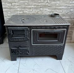 an old fashioned stove is sitting in front of a brick wall and flooring area