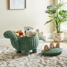 a basket with stuffed animals in it sitting on the floor next to a potted plant