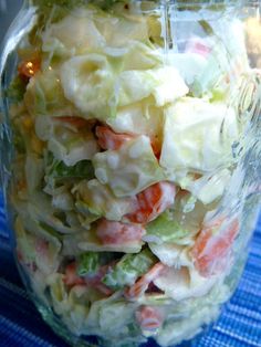 a glass jar filled with salad sitting on top of a blue table cloth