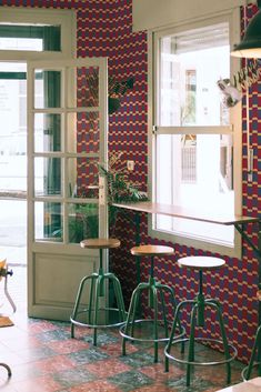 three stools in front of a window with colorful tiles on the wall behind them