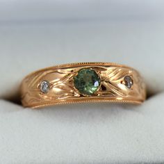 a gold ring with a green stone surrounded by diamonds