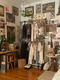 a room filled with lots of clothes and pictures on the wall next to a bed