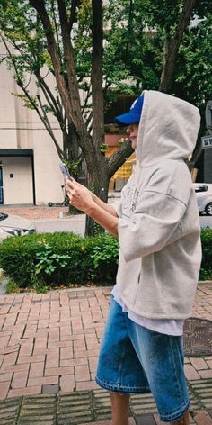 a man in a hoodie is looking at his cell phone while walking down the street