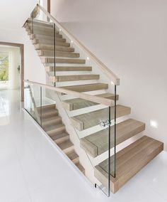 a staircase with glass railing and wooden handrail