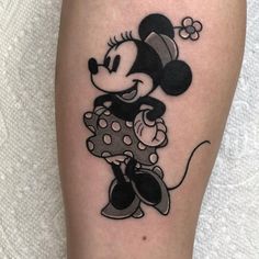 a black and white mickey mouse tattoo on the right leg, with a flower in it's hair