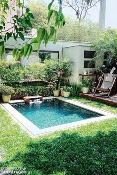 a small pool in the middle of a yard with lawn chairs and potted plants