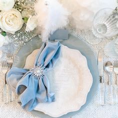 a table setting with white flowers and blue napkins