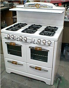 an old fashioned white stove with four burners and two ovens on the front