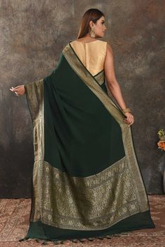 Be vision of elegance on special occasions in this beautiful bottle green crepe sari. The saree is enhanced with antique zari border. It comes with a matching blouse piece. Disclaimer: The actual product may vary slightly from the image. These are custom orders, hence expect slight variation in color, placement of the motif or buta. ESTIMATED DELIVERYBecause this is a custom order, it would take about 4 weeks from the date of purchase. RETURN POLICYThis product is a custom order and cannot be re Green Saree With Border For Eid, Green Border Saree For Eid, Dark Green Saree With Zari Work, Dark Green Saree With Cutdana For Traditional Wear, Elegant Green Dupatta With Border, Dark Green Cutdana Saree, Traditional Dark Green Wear With Dupatta, Dark Green Traditional Wear For Diwali, Green Zari Weaving Georgette Traditional Wear