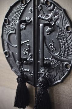 two black metal door handles with tassels on each one and an ornate design