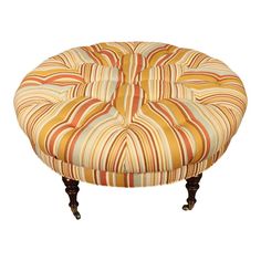 a round foot stool with an orange and yellow striped upholstered fabric on it