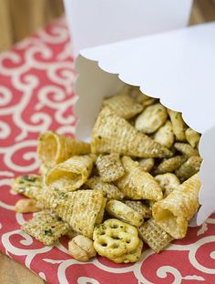 a box filled with cheetos sitting on top of a red and white tablecloth