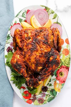 grilled chicken on a floral plate with onions and lemon wedges next to it