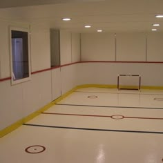 an empty hockey rink with yellow and red lines on the floor is seen in this image