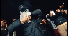 a group of people standing around each other with money in their hands and one person covering his face