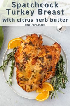 a white plate topped with meat covered in herbs and surrounded by sliced orange wedges