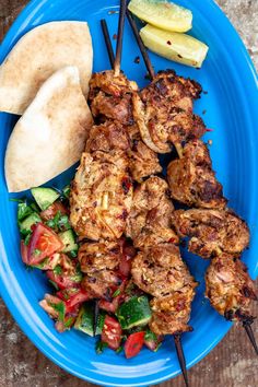 a blue plate topped with meat and veggies next to a pita bread