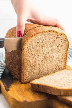 a person cutting bread with a knife on a cutting board