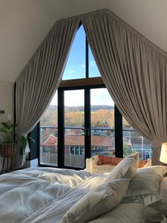 a bedroom with a large window and white bedding, along with two lamps on either side