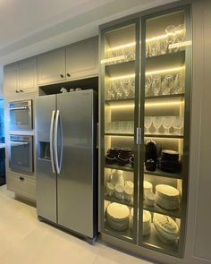 a stainless steel refrigerator in a kitchen with glass doors and shelves filled with plates, bowls and glasses