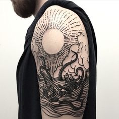 a man with a black and white tattoo on his arm is looking at the sun