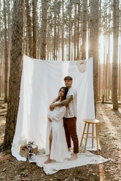 a man and woman standing next to each other in front of a white sheet on the ground