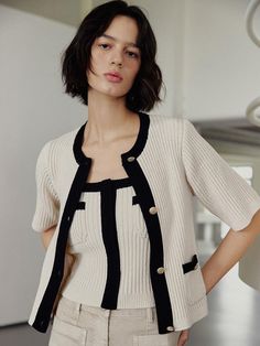 Classic knit cardigan featuring the soft cream and black color combination. Made of the stretchy and lightweight cotton blended fabric that has comfortable fit. The button-up style, slightly cropped length, and the golden button detail are featured. We recommend style with the knit bustier top to create set-up look. - Rounded neckline and half-sleeved design- Button-up design with golden buttons detail- Welt pockets with golden button detail- Relaxed fit and slightly cropped length- Soft and stretchy ribbed cotton blended fabric Chic Cream Sweater With Buttons, Chic Knit Top With Button Closure, Chic Cream Cardigan With Button Closure, Chic Beige Button-up Cardigan, Elegant Cream Knit Top For Work, Classic Beige Knit Top For Work, Elegant Beige Knit Top For Work, Chic Beige Knit Top For Work, Black Color Combination