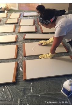 a woman in white shirt and yellow gloves working on tile