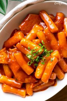 a white bowl filled with carrots covered in sauce