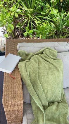 an open laptop computer sitting on top of a wicker chair next to a blanket