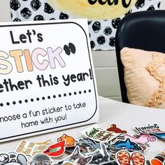 a table topped with lots of stickers next to a sign that says, let's stick together this year