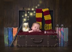 a baby is sleeping in a suit case with harry potter scarves on it's head