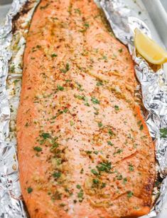 a piece of cooked salmon sitting on top of aluminum foil covered in seasoning and garnish