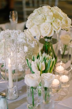 white flowers and candles are arranged in vases