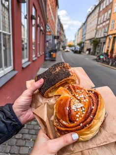 a person holding up a sandwich in front of a building