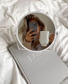 a woman taking a selfie with her cell phone in front of a round mirror