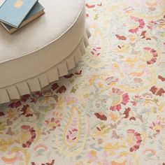 an area rug with various colors and designs on the floor next to a round ottoman