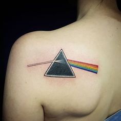 a woman's shoulder with a pink floyd triangle tattoo and a rainbow on it