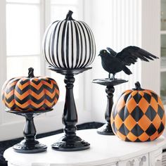 three black and orange pumpkins sitting on top of a white table in front of a window