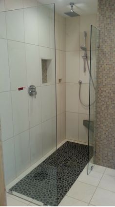 a walk in shower sitting next to a toilet and tiled floored bathroom area with glass doors