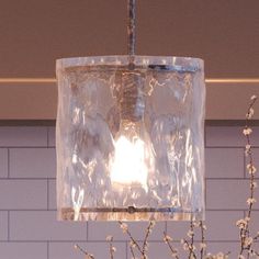 a glass light hanging from a ceiling in a room with blue tiles on the wall