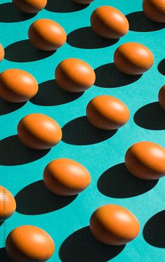 an array of orange eggs sitting on top of a blue surface by jovo studio for stocks & bond