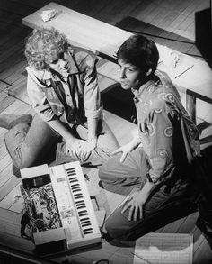 two people sitting on the floor next to an electronic keyboard