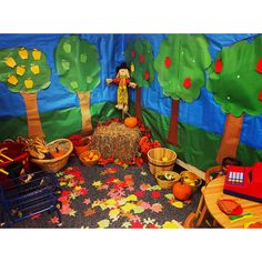 a child's play room with fall leaves and pumpkins on the floor, including a scarecrow