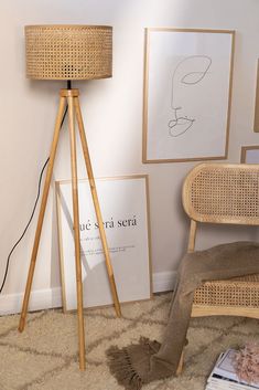 a floor lamp in the corner of a room with pictures on the wall behind it